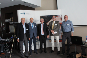 Fünf Männer posieren bei einer Veranstaltung vor einer weißen Kulisse mit dem Logo der 'GSP Gesellschaft für Sicherheitspolitik e.V.'.
