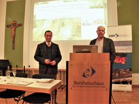 Zwei Männer halten einen Vortrag im Bonifatiushaus Fulda über die Bundeswehr und ihre Tradition, Projektor im Hintergrund.