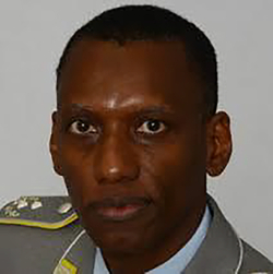 Porträt eines Mannes mit dunkler Haut, kurzen Haaren, in Militäruniform mit Schulterklappen, blickt direkt zum Betrachter.