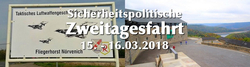 Schild für Fliegerhorst Nörvenich mit Jets und Text 'Sicherheitspolitische Zweitagesfahrt 15.-16.03.2018' über Gebäude und Tal.