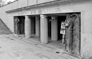 Monochromes Foto des Hartmannswillerkopf-Denkmal-Eingangs mit Säulen, geschnitzten Engeln und Treppe links.