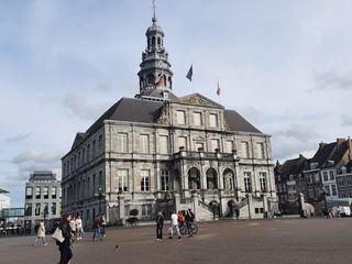 Das prächtige Stadhuis von Maastricht, ein historisches Steingebäude mit hohem Glockenturm, auf einem belebten Platz.