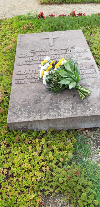 Ein flacher Grabstein mit Inschriften 'Graf von Hardenberg' und 'Gräfin', verziert mit einem Strauß gelber und weißer Blumen.