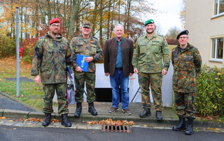 Fünf Männer, darunter vier Soldaten in deutschen Flecktarn-Uniformen und ein Zivilist, posieren im Herbst.
