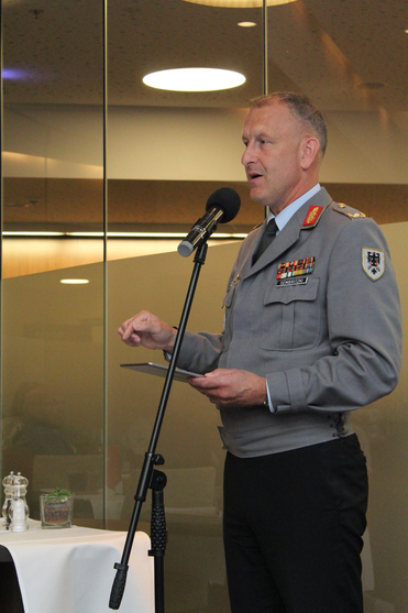 Ein Offizier in Uniform mit Namensschild 'Sembritzki' spricht ins Mikrofon und hält ein Tablet.