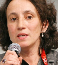 Die französische Filmregisseurin Claire Denis spricht in ein Mikrofon, mit dunklem lockigem Haar und einem Perlenohrring.