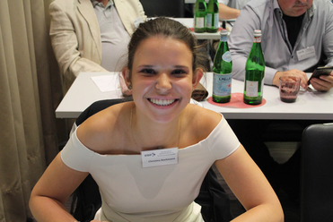 Eine lächelnde Christina Bachmann, mit Namensschild, sitzt an einem Tisch mit San Pellegrino Flaschen bei einem GSP-Event.