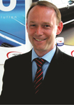 Dr. Martin Lobert Ein lächelnder Mann im schwarzen Anzug mit rot gestreifter Krawatte vor einem blauen Hintergrund mit Produktwerbung.