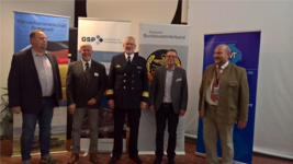 Fünf Männer stehen lächelnd vor Bannern von Panzerkameradschaft, GSP und BundeswehrVerband auf einer Veranstaltung.