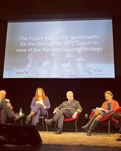 Podiumsdiskussion zur zukünftigen Rolle der Bundeswehr mit vier Teilnehmern und einer Leinwand mit Thema und Logos.