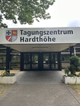 Der Eingang des Tagungszentrums Hardthöhe, gekennzeichnet durch ein Schild mit dem Namen und einem Wappen mit Eisernem Kreuz, Löwen, Fluss und Feder.