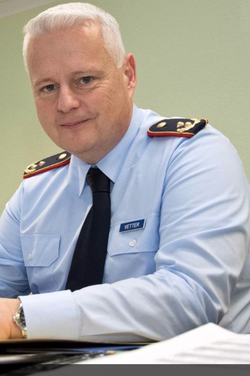 Offizier Vetter in hellblauer Uniform mit Schulterklappen, lächelt in die Kamera.