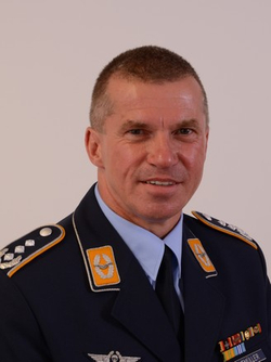Porträt eines deutschen Offiziers, K. Müller, in dunkelblauer Uniform mit Abzeichen, leicht lächelnd.