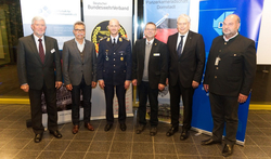 Gruppenfoto von sechs Männern, darunter ein Soldat in Uniform, vor Bannern deutscher Sicherheits- und Militärverbände.