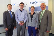 Vier Personen, drei Männer und eine Frau, stehen lächelnd vor Bannern der Atlantischen Akademie und GSP.